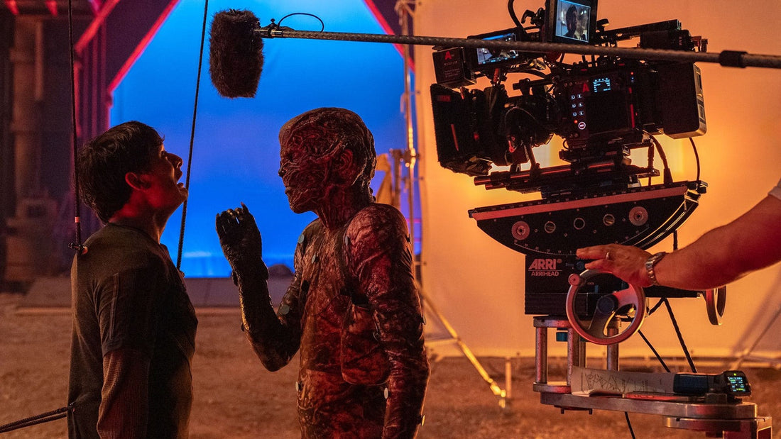 Plano de rodaje de Stranger Things: cámara, pértiga de sonido y fondo azul frente a un actor maquillado de criatura