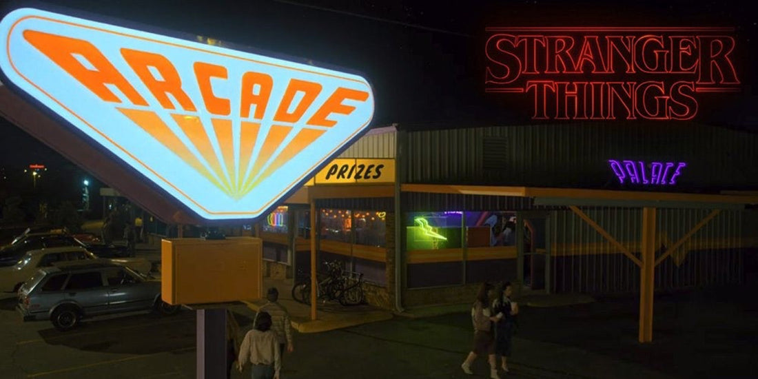 El rótulo de neón ARCADE del Palace encendido de noche en Stranger Things, siluetas ante la entrada