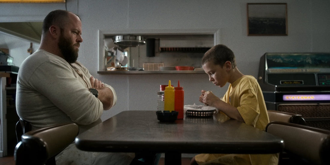 Benny Hammond mira a Once comer en la mesa del Benny's Burgers