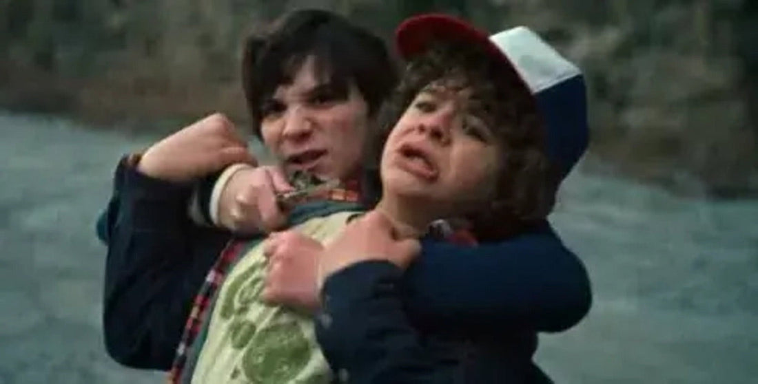 Un chico del colegio agarra a Dustin por el cuello, sobre la cantera
