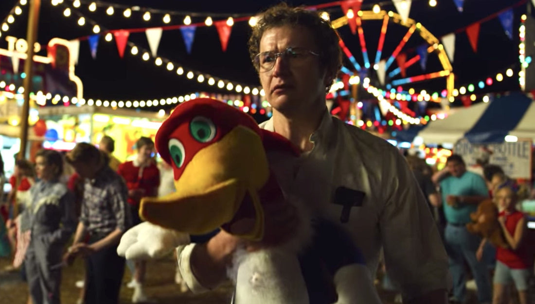 Alexei en la feria, un pájaro de peluche en los brazos y la noria detrás.