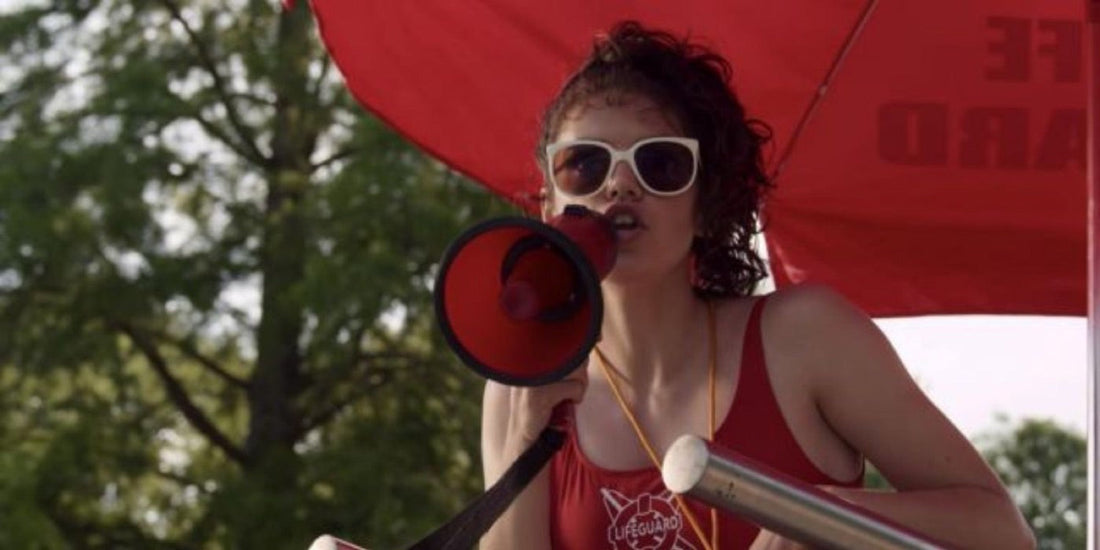 Heather Holloway, socorrista, habla por un megáfono al borde de la piscina.