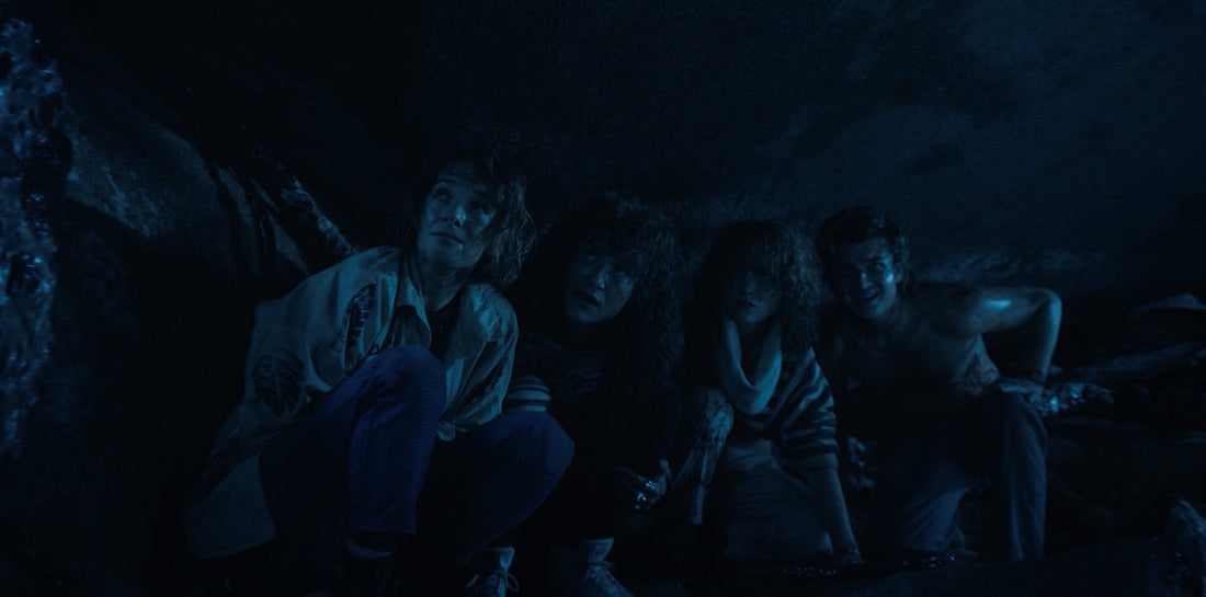 Nancy, Robin, Eddie y Steve, empapados, bajo la roca tras el salto.