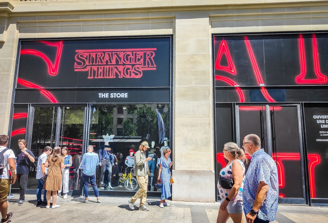 Fachada iluminada de una avenida parisina, escaparate oscuro y letras rojas