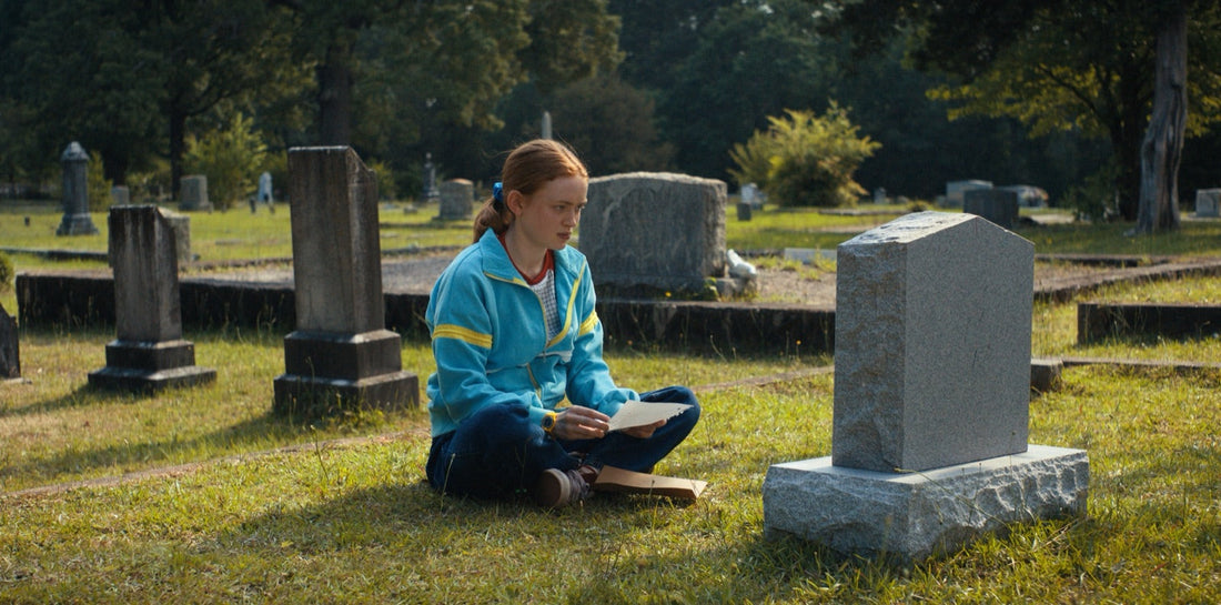 Max sentada en un cementerio, una carta abierta sobre las rodillas, Stranger Things temporada 4 episodio 4