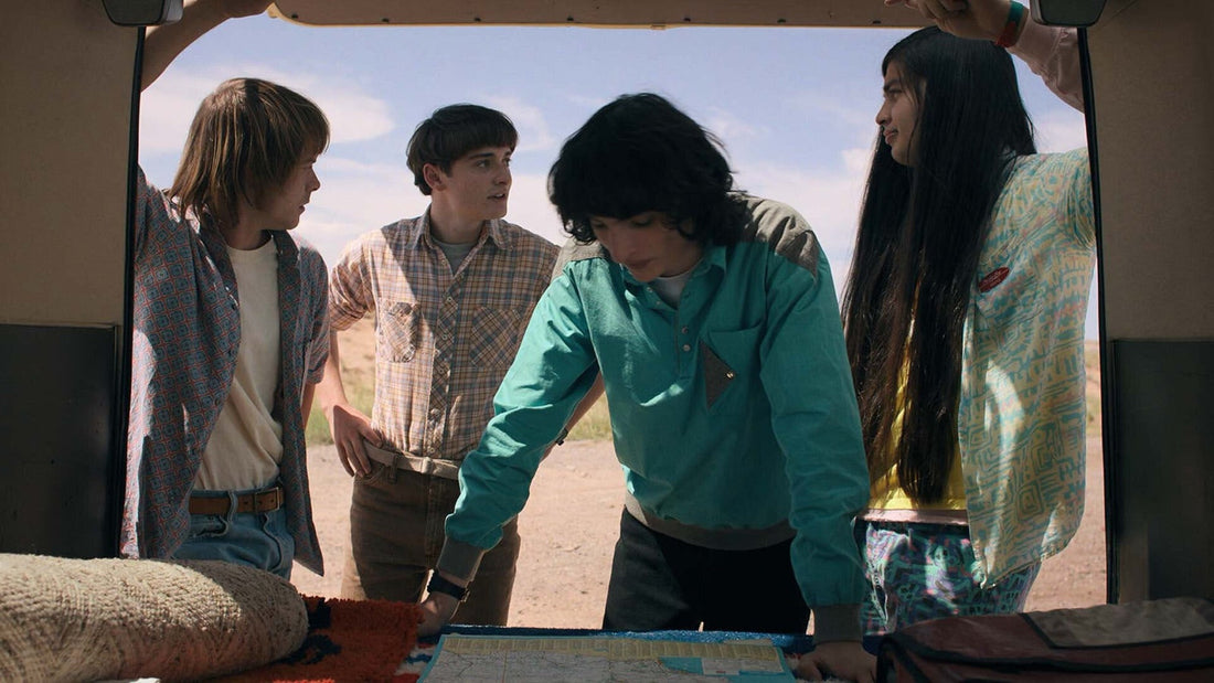Cuatro adolescentes inclinados sobre un mapa, atrás en una furgoneta, Stranger Things temporada 4 episodio 5