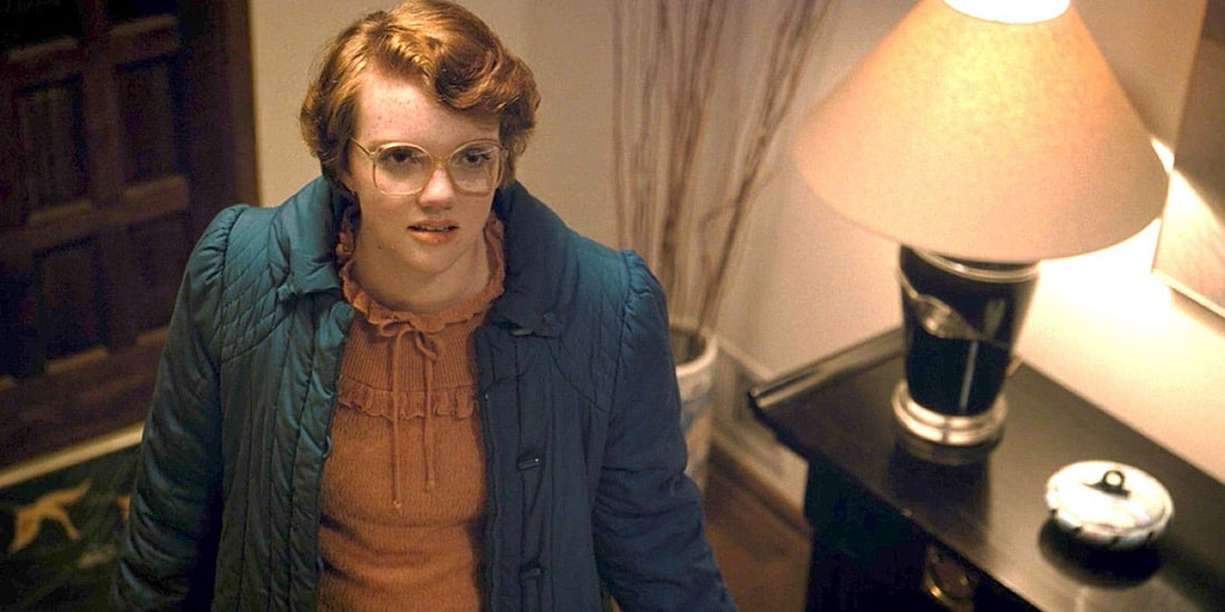 Shannon Purser como Barbara Holland, gafas y abrigo azul, en una entrada.